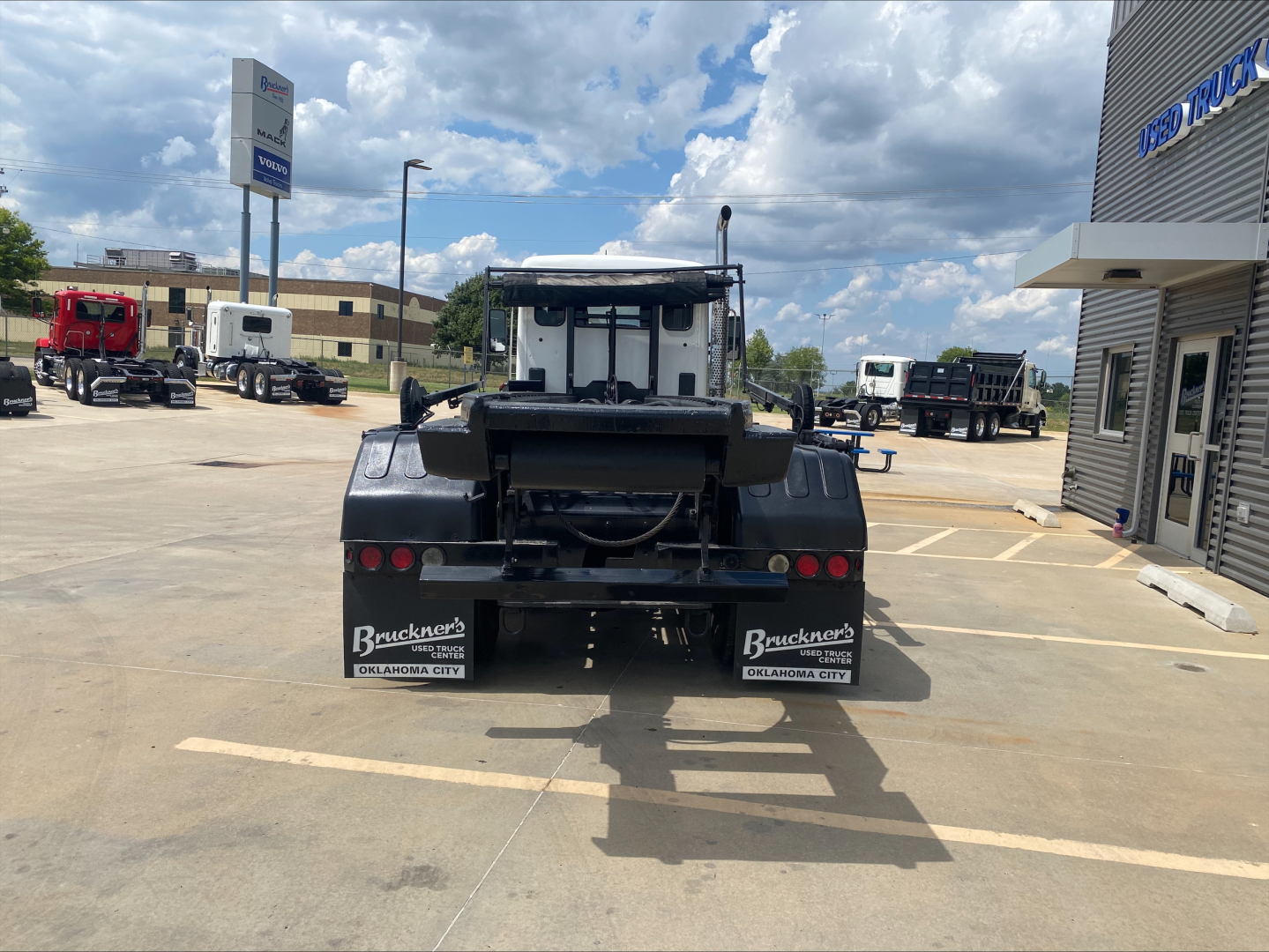 Kenworth T880 roll-off truck rear view showing bumper, taillights, and branding plates in a dealership lot.