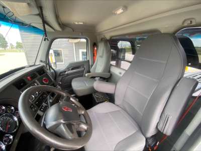 Kenworth T880 truck cab interior showing steering wheel, dashboard, gray cloth seats, and driver seat with armrest.
