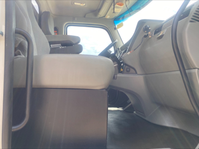 Kenworth T880 cab interior showing driver seat and dashboard with steering wheel, windshield, and pedals visible.