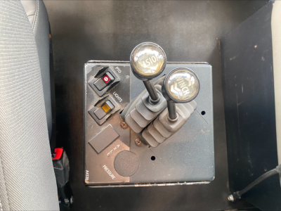 Kenworth T880 control panel with two joystick-like levers labeled PTO and other controls, view inside cab floor area.