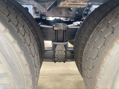 Kenworth T880 chassis view showing dual rear axles with leaf spring suspension and driveshaft area between tires.