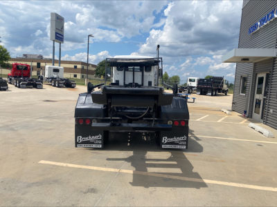 Kenworth T880 roll-off truck rear view showing bumper, taillights, and branding plates in a dealership lot.