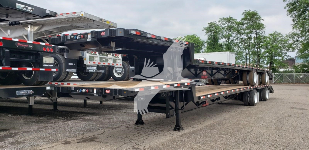 Beavertail trailer on a lowboy with multiple axles and loading ramps, viewed from side angle.
