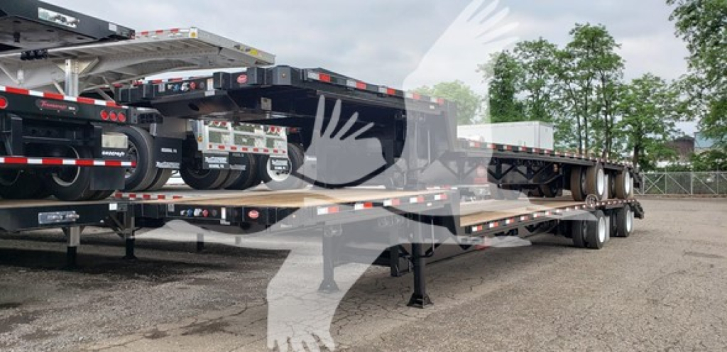 Trailer in a yard showing a Dorsey Beavertail lowboy trailer with multiple axles and a folded ramp, side rails, and undercarriage components visible.