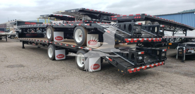 Trailer deck showing stacked beavertail trailers with black frames, white wheels, and red and white reflectors. Visible branding on mud flaps reads 'Dorsey' and multiple levels of the beavertail trailers.