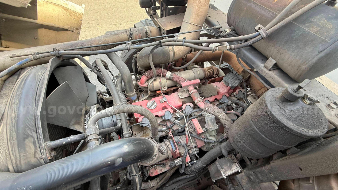 Diesel engine bay of a 2016 Autocar Xpeditor showing red engine block with various hoses, pipes, and air intake, plus surrounding components.