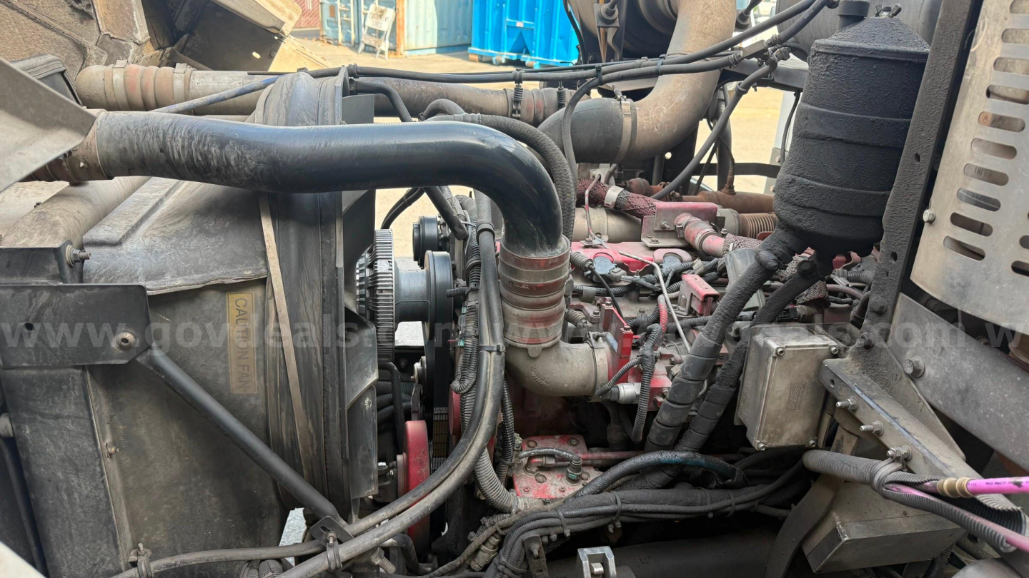 Autocar Xpeditor truck engine bay showing hoses, radiator, and engine components with visible wiring and components.