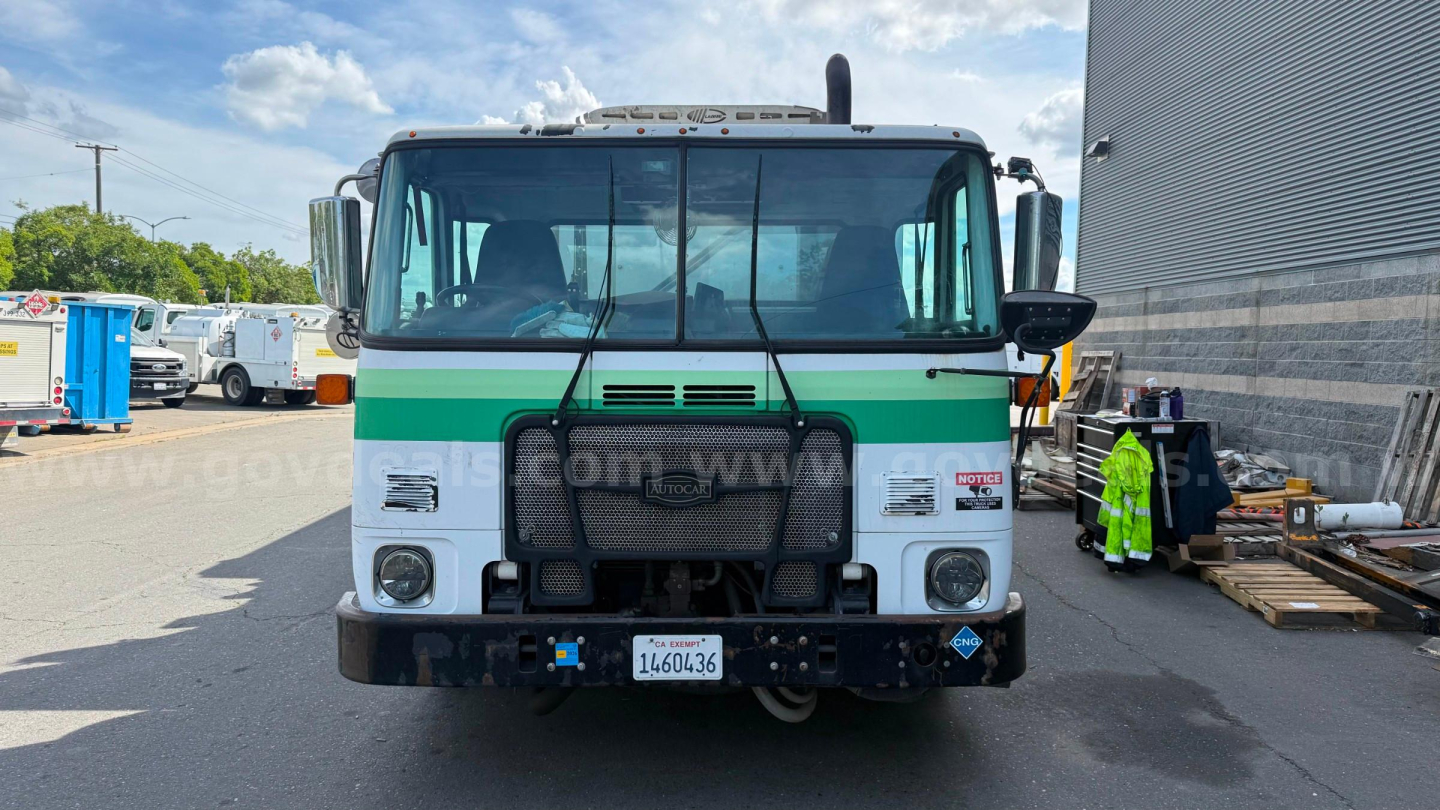 Autocar XPeditor truck front view showing grille, green stripe, headlights, bumper, and license plate area.