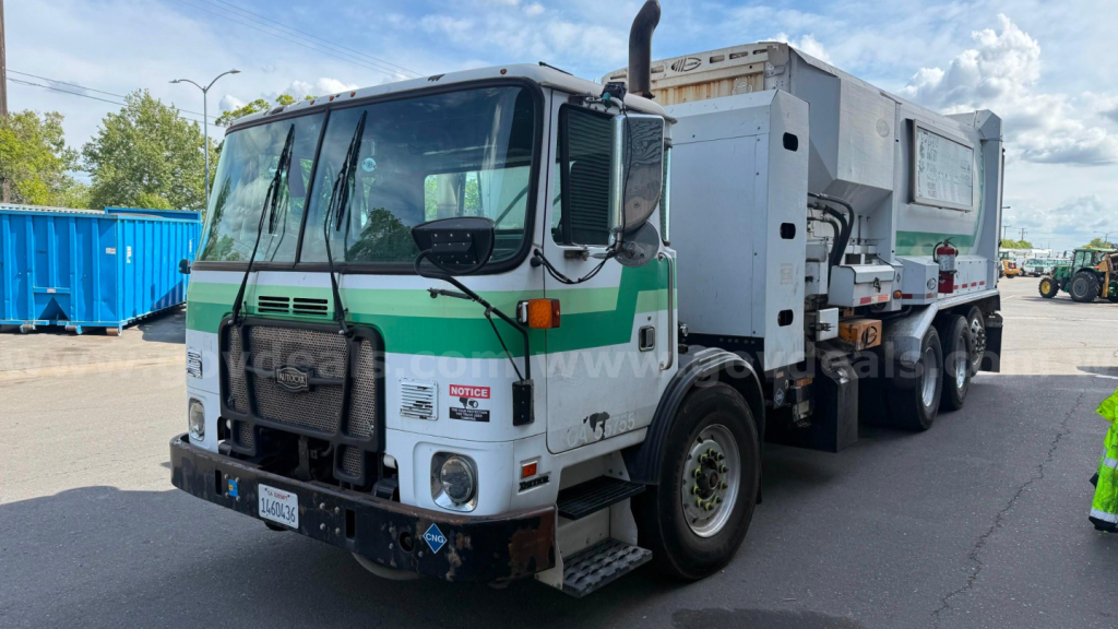 Autocar Xpeditor truck shown from front-left side with a large dump body, green stripe, and logo on door; VIN plate not legible, stock number 4450-99 visible; garbage category.
