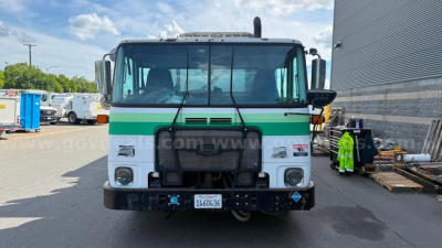 Autocar XPeditor truck front view showing grille, green stripe, headlights, bumper, and license plate area.