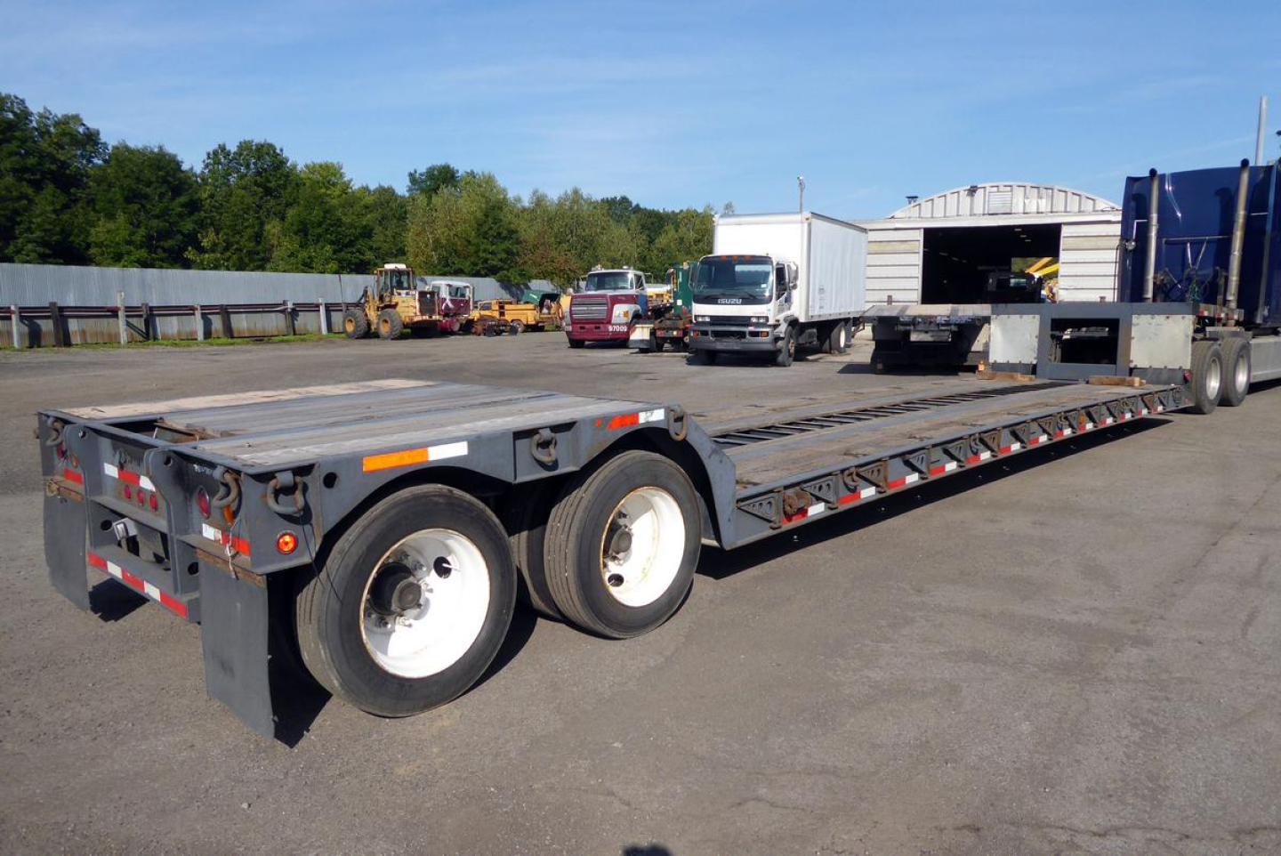 Low-angle view of a Fontaine 302WDMR-LT drop deck trailer showing dual rear axles and long flatbed.