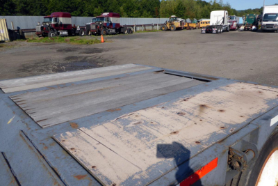 Trailer deck of a Fontaine 302WDMR-LT with worn metal surface and reflective orange safety tape in view.