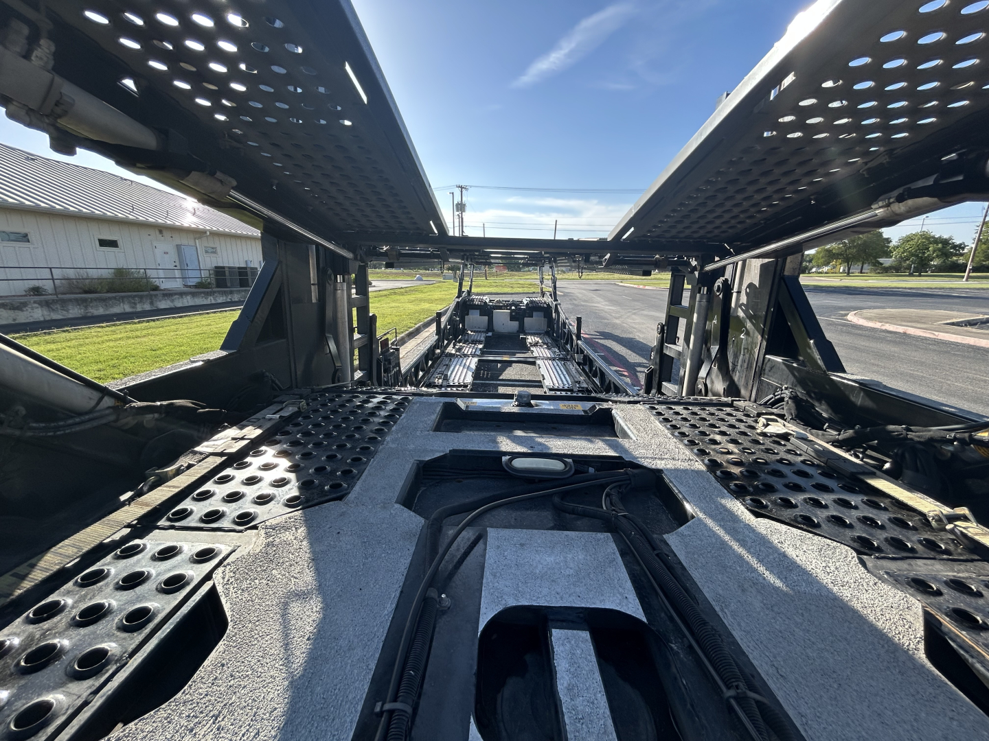 Inside view of a 2022 Cottrell CX-5308LT car carrier trailer showing the loading bays, walkways, and mechanical frame with perforated metal panels.