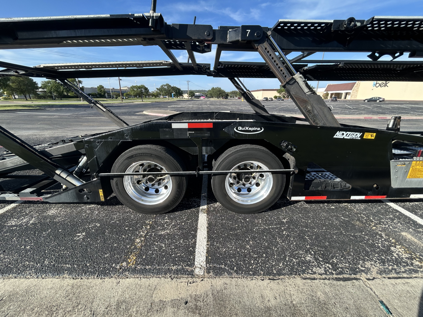 Semi-trailer show side view of a black car carrier trailer with dual axles and metal frame, CX-5308LT branding near midsection.