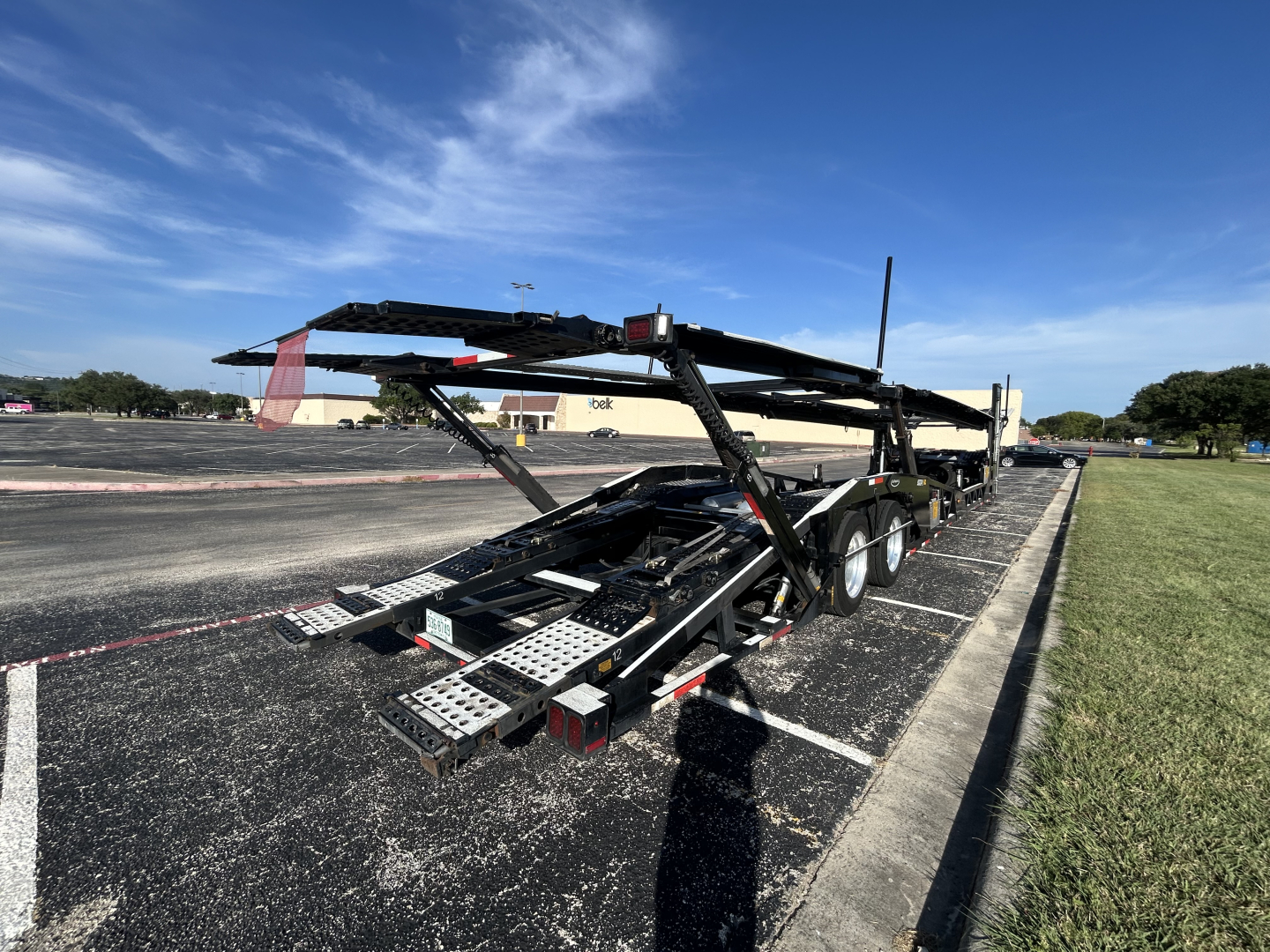 CX-5308LT car carrier trailer with dual-axle setup and loading ramps, viewed from rear left, showing metal deck and wheel wells.