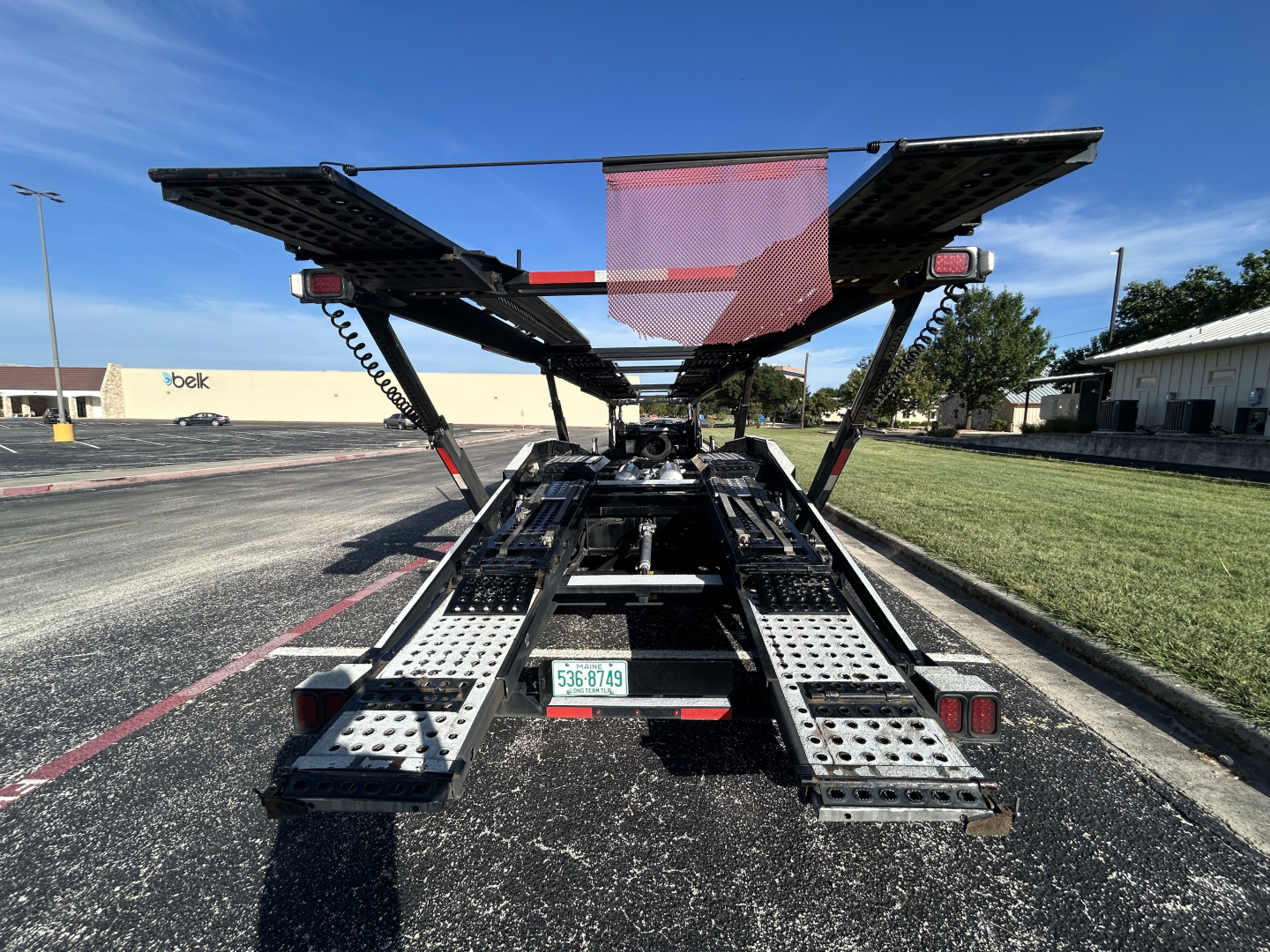 Rear view of a 2022 Cottrell CX-5308LT car carrier trailer showing dual fold-out ramps and loading deck with metal perforated steps.