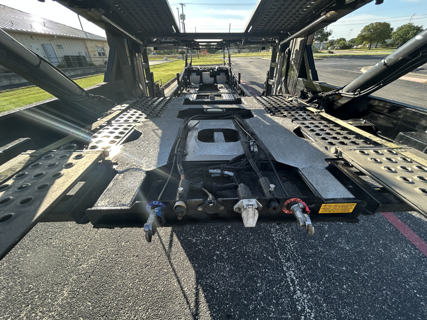 Trailer deck of a 2022 Cottrell CX-5308LT car carrier showing the gooseneck mount and suspension with textured aluminium cross members and hook points.