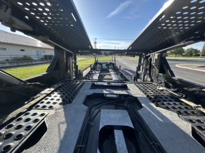 Inside view of a 2022 Cottrell CX-5308LT car carrier trailer showing the loading bays, walkways, and mechanical frame with perforated metal panels.