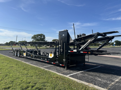 Trailer in a parking lot, CX-5308LT tilt car carrier with black frame and multiple deck ramps, visible model plate/labels along side.