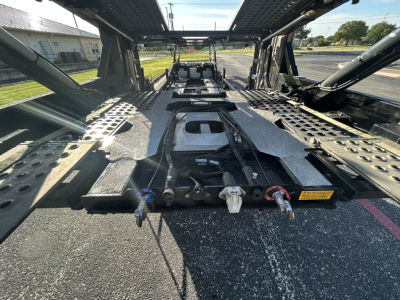 Trailer deck of a 2022 Cottrell CX-5308LT car carrier showing the gooseneck mount and suspension with textured aluminium cross members and hook points.