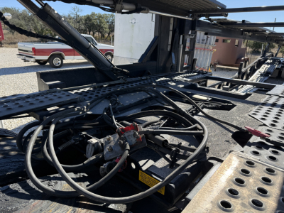 Trailer hydraulics and control lines on a 2022 Cottrell CX-5308LT car carrier trailer showing hoses, hydraulic components, and underframe.
