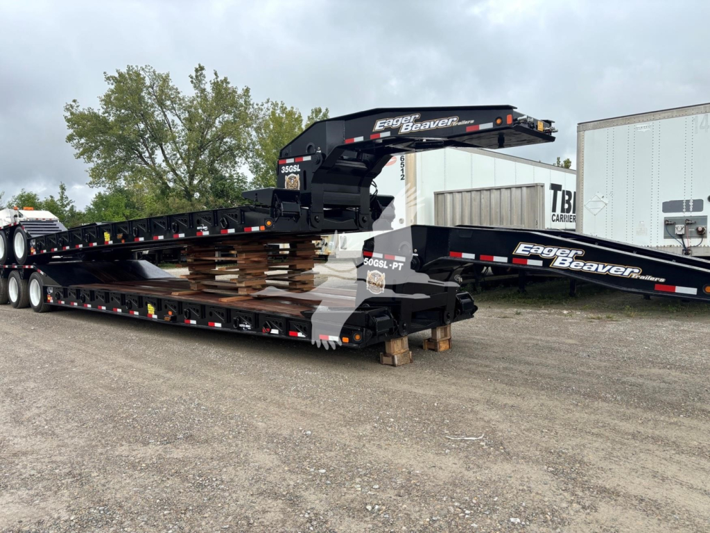 Lowboy trailer setup with stacked Eagle Beaver 50Gsl-Pt landing gear and hydraulic gooseneck sections, brand text 'Eagle Beaver' on the arms, multiple safety reflectors and pallets under the deck.