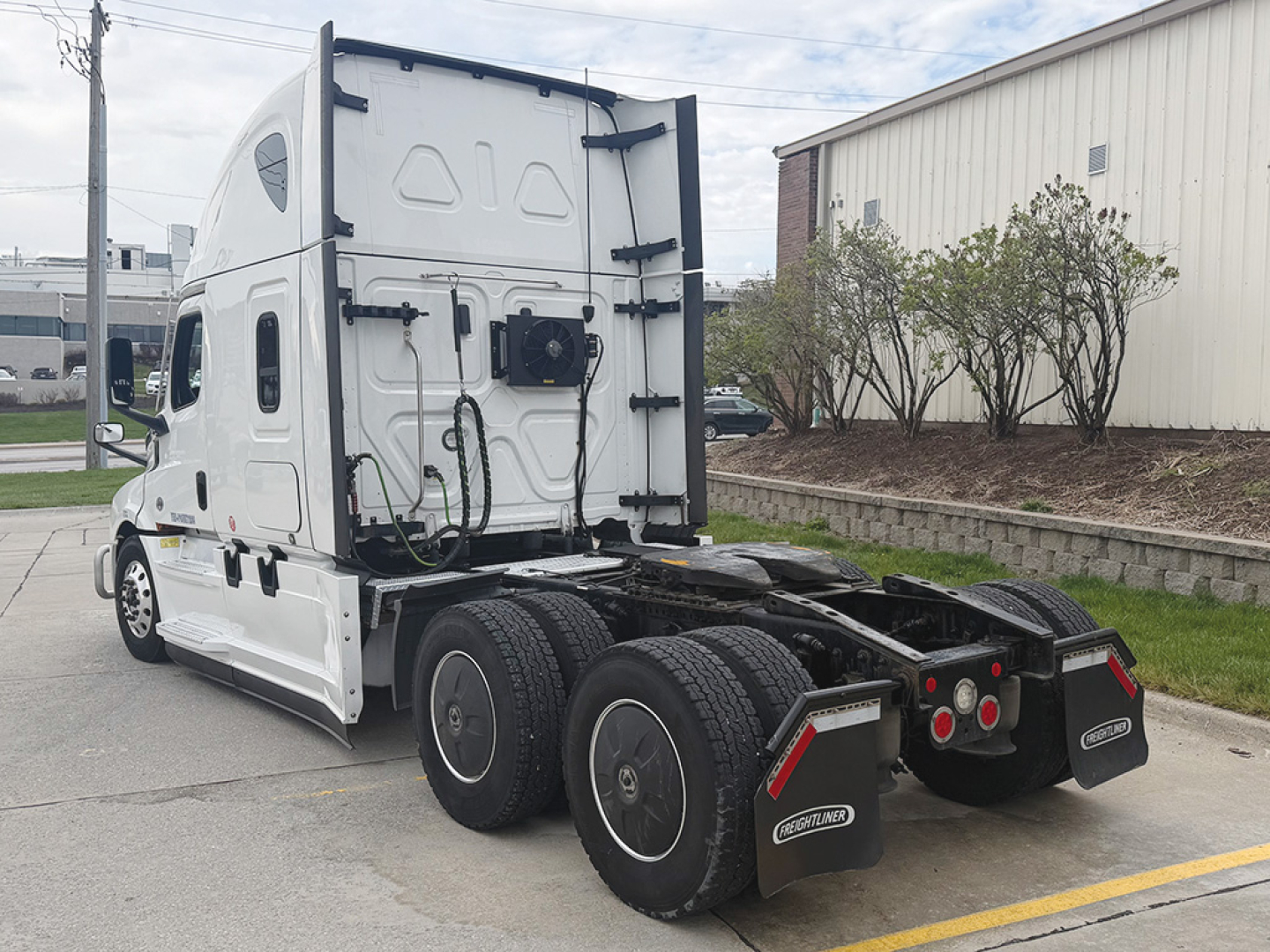 Freightliner Cascadia126 tractor rear view showing tandem drive axles, mud flaps, and sixth wheel assemblies with electrical connectors and chassis details.