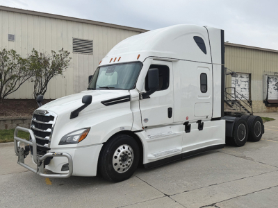 Truck in a parking lot: white 2023 Freightliner Cascadia126 sleeper cab with aerodynamic hood, grille guard, side access steps, and dual rear axles; no visible logos legible besides generic truck features.