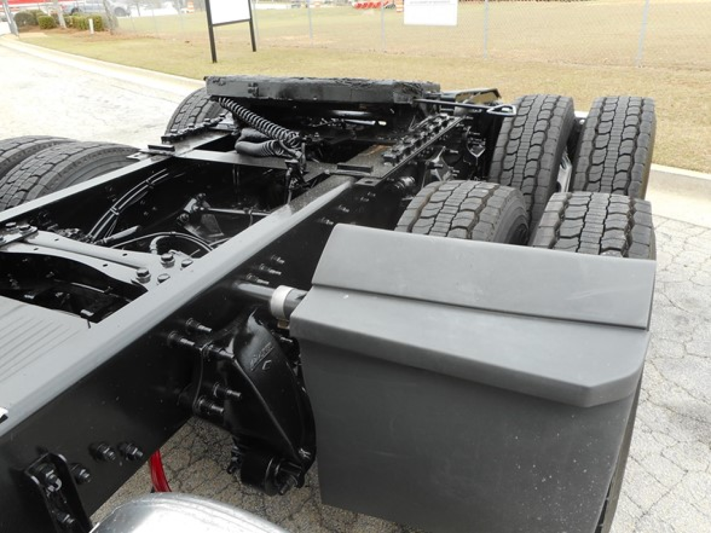 Chassis behind Freightliner Cascadia 126 show large dual rear axle with tires and undercarriage components; fuel tanks and frame visible