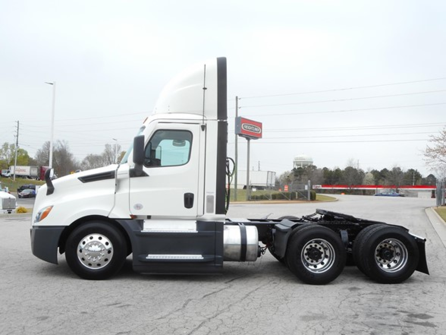 Freightliner Cascadia 126 day cab side profile showing front half with sleeper exhaust stack and chassis, white cab, two rear axles, no trailer.