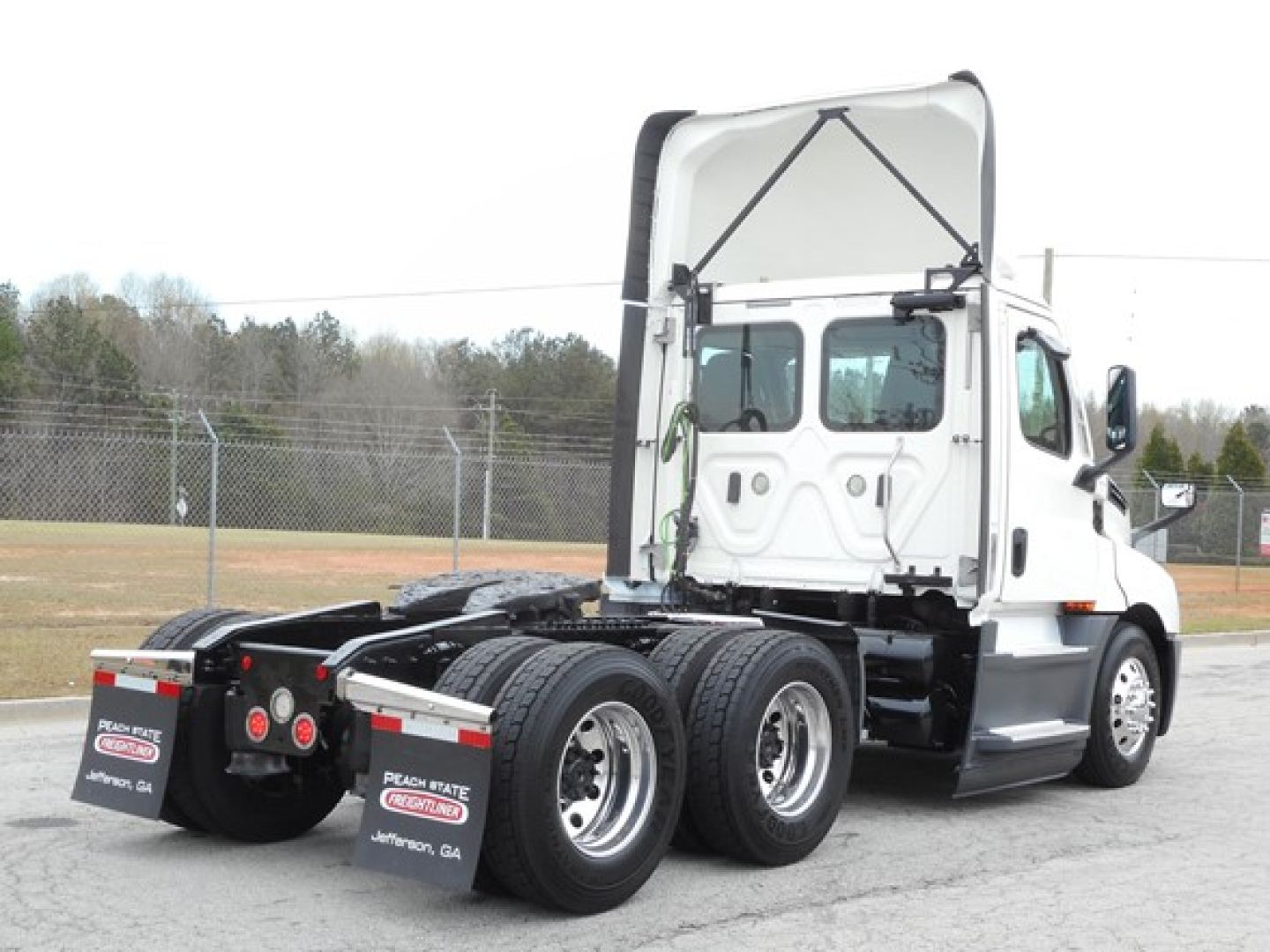 Truck chassis and cab view showing Freightliner Cascadia 126 with rear dual-axle setup and raised cab hatch.