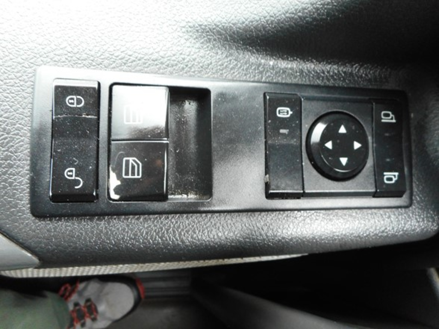 Dashboard window control panel showing mirror adjustment switch and window/lock controls in a Freightliner Cascadia cab.