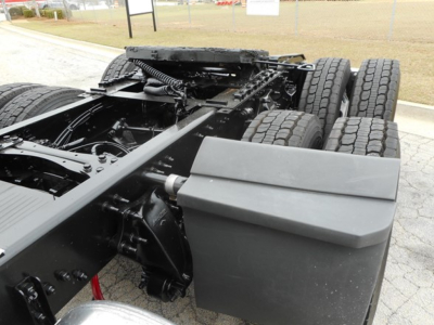 Chassis behind Freightliner Cascadia 126 show large dual rear axle with tires and undercarriage components; fuel tanks and frame visible