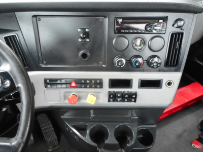 Dashboard of a Freightliner Cascadia 126 cab showing instrument panel, vents, switches, and cupholders.