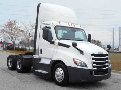 Truck cab showing Freightliner Cascadia 126 day cab with sleeper pod and dual rear axles, white exterior and chrome front grille.