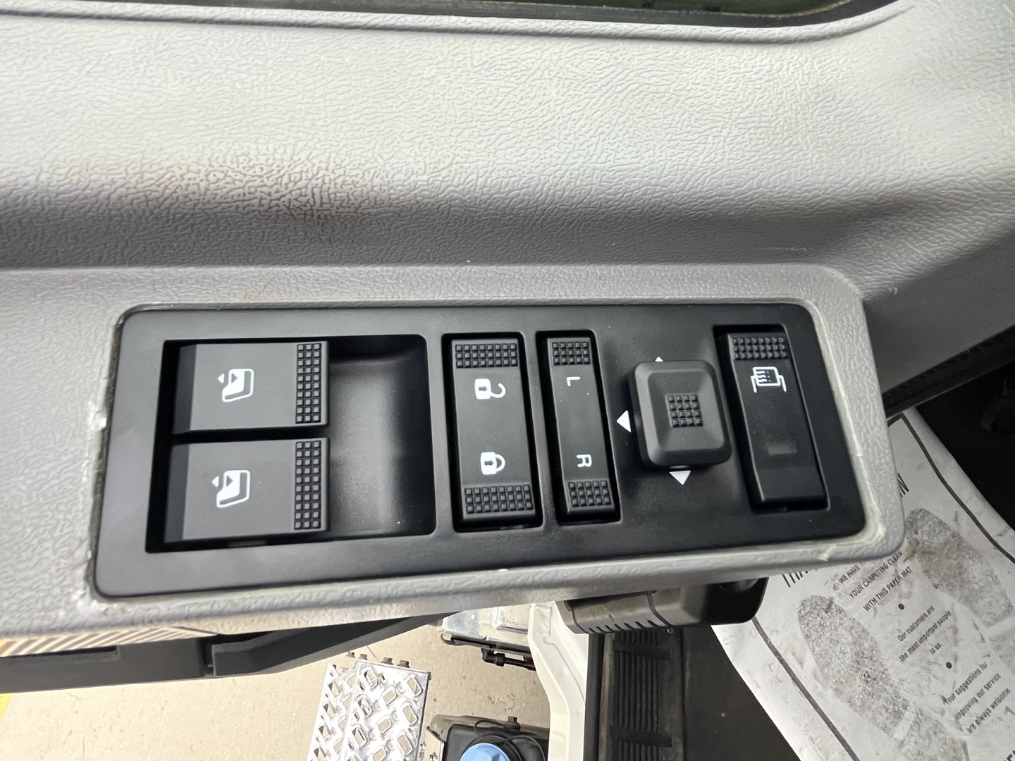 Truck driver's door panel with window/lock controls and mirror adjustment switches visible in the cab.