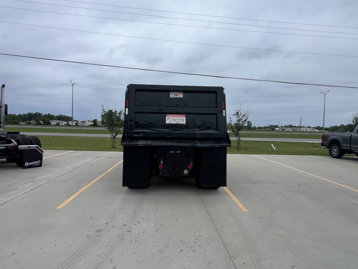 Rear view of a used 2020 Mack GR64F dump truck showing the back of the dump bed and hitch area.