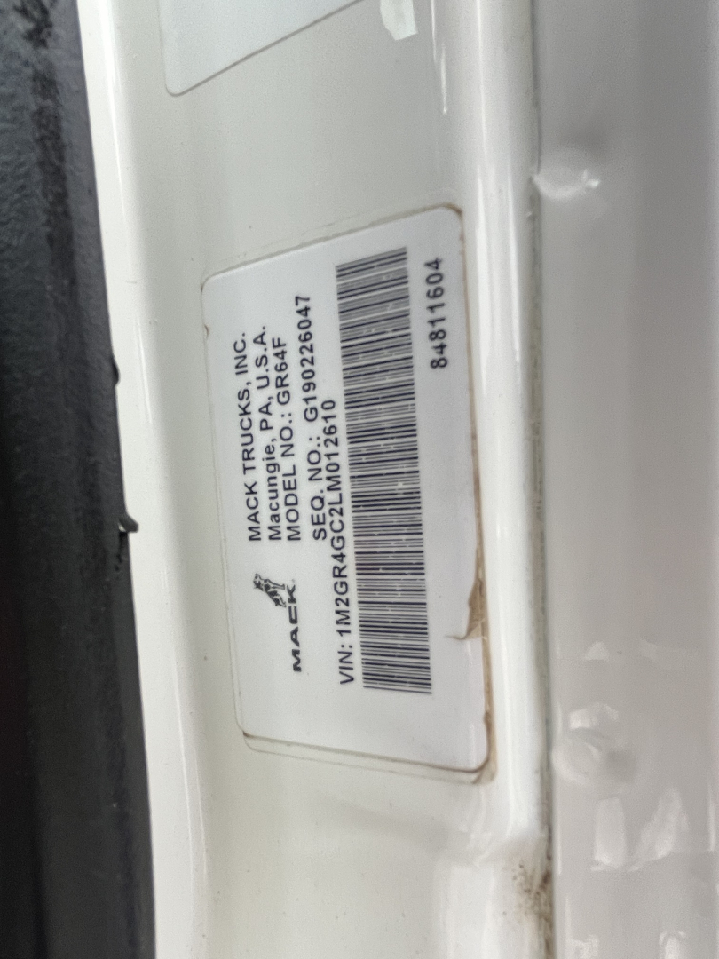Label on Mack truck door jamb showing VIN, stock number, and model details. Text includes 'MACK TRUCKS, INC.', 'MACK TRUCKS', 'GR64F', 'VIN: 1M2GR4GC2LM012610', 'Stock NO: 2604', barcode, and other serials.