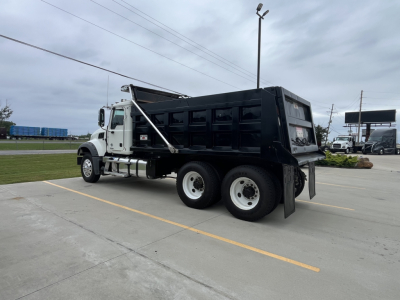Truck side view showing a black dump bed on a white 2020 Mack GR64F with dual rear axles.