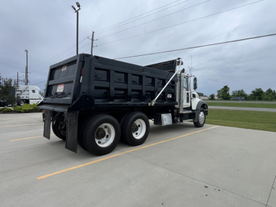 Dump truck 2020 Mack GR64F with black dump body in side rear view showing DOT sticker and rear taillamps.