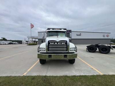 Mack GR64F dump truck front view showing grille with MAEK emblem, chrome bumper, large side mirrors, on a dealership lot.