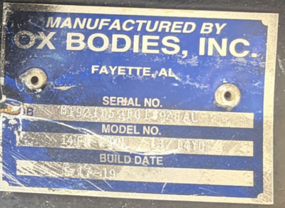 Blue metal plate with 'Manufactured by Ox Bodies, Inc.' and text blocks showing location Fayette, AL, serial no, model no, and build date.