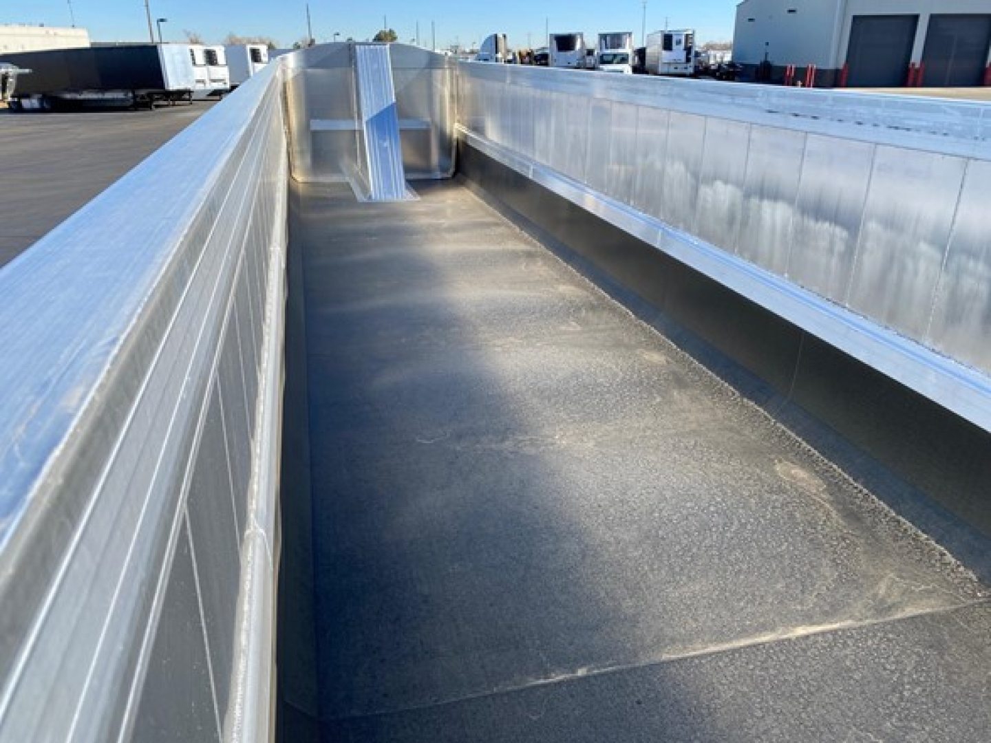 Flatbed trailer interior showing aluminum side rails and steel floor with clean, reflective metal surfaces.