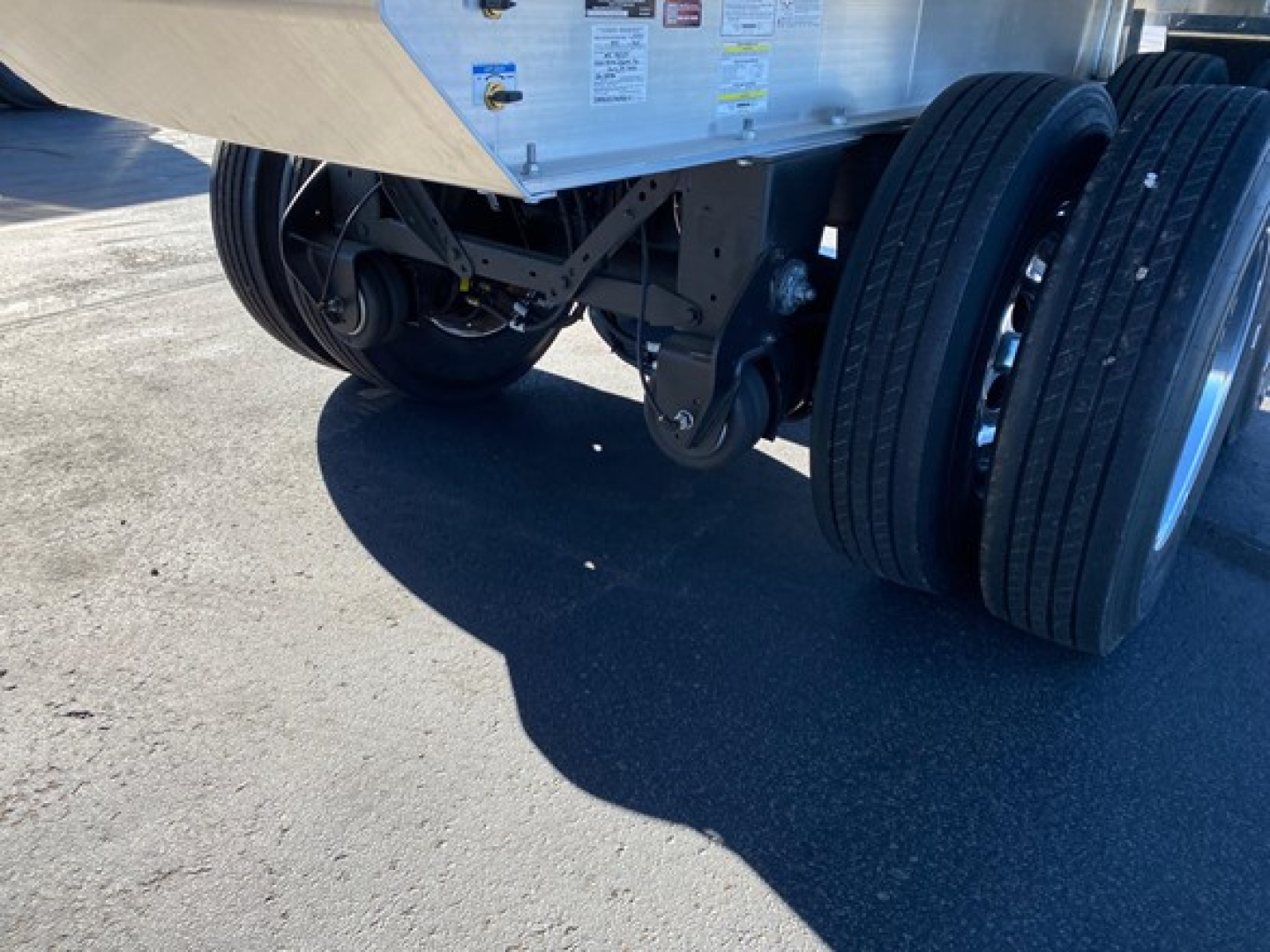 Trailer axle area showing dual rear tires and part of chassis with metal framework and suspension components.