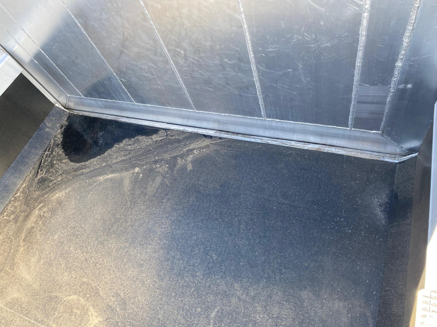 Trailer interior showing metal walls and a black bed with slight dust; no readable model text visible.