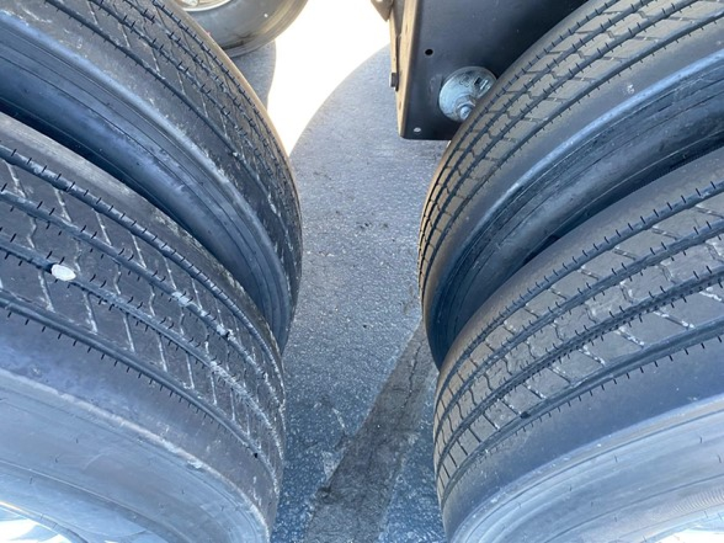 Tandem trailer tires mounted on axle with dual wheels visible on each side, highway tread, part of trailer frame in view.