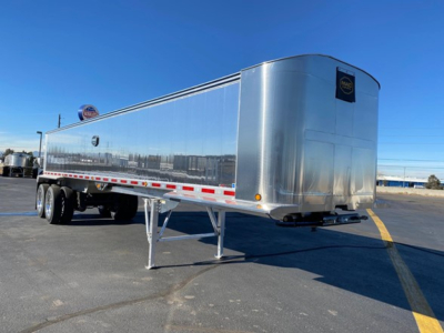 Trailer side view showing aluminum dump trailer with dual rear axles and front landing gear.