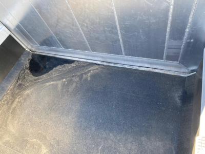 Trailer interior showing metal walls and a black bed with slight dust; no readable model text visible.