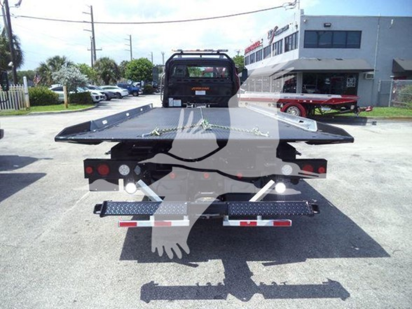 Flatbed tow truck rear view showing heavy-duty platform and winch with LED taillights, trailer hitch, and bumper guards.