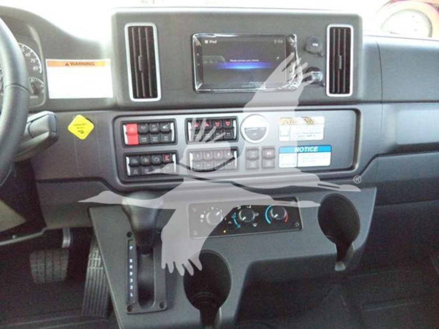 Dashboard of a freightliner m2-106 plus cockpit showing central touchscreen, control panel, and gear shifter area.